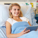 girl using tablet in hospital bed