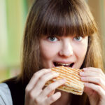 Portrait of young woman with sandwich