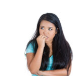 Scared anxious young woman biting fingernails white background